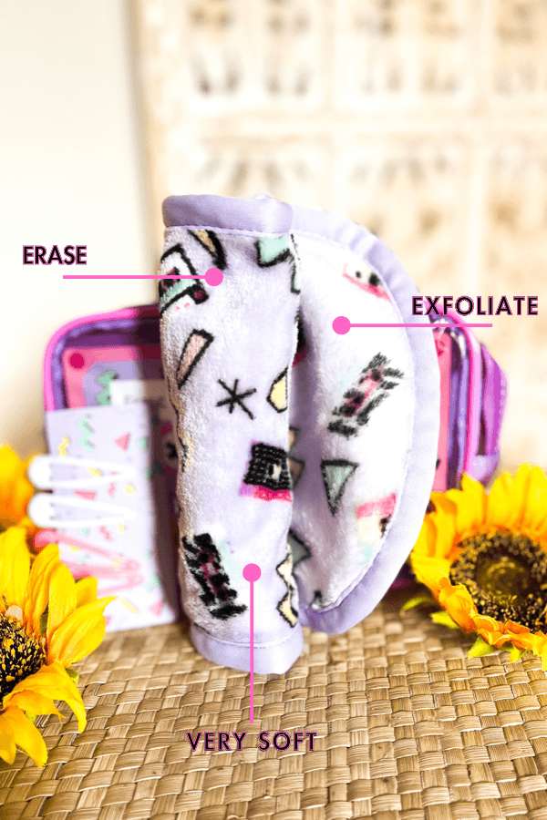 Purple plush makeup remover cloth with 90s patterns labeled erase, exfoliate, and very soft beside sunflowers and pouch