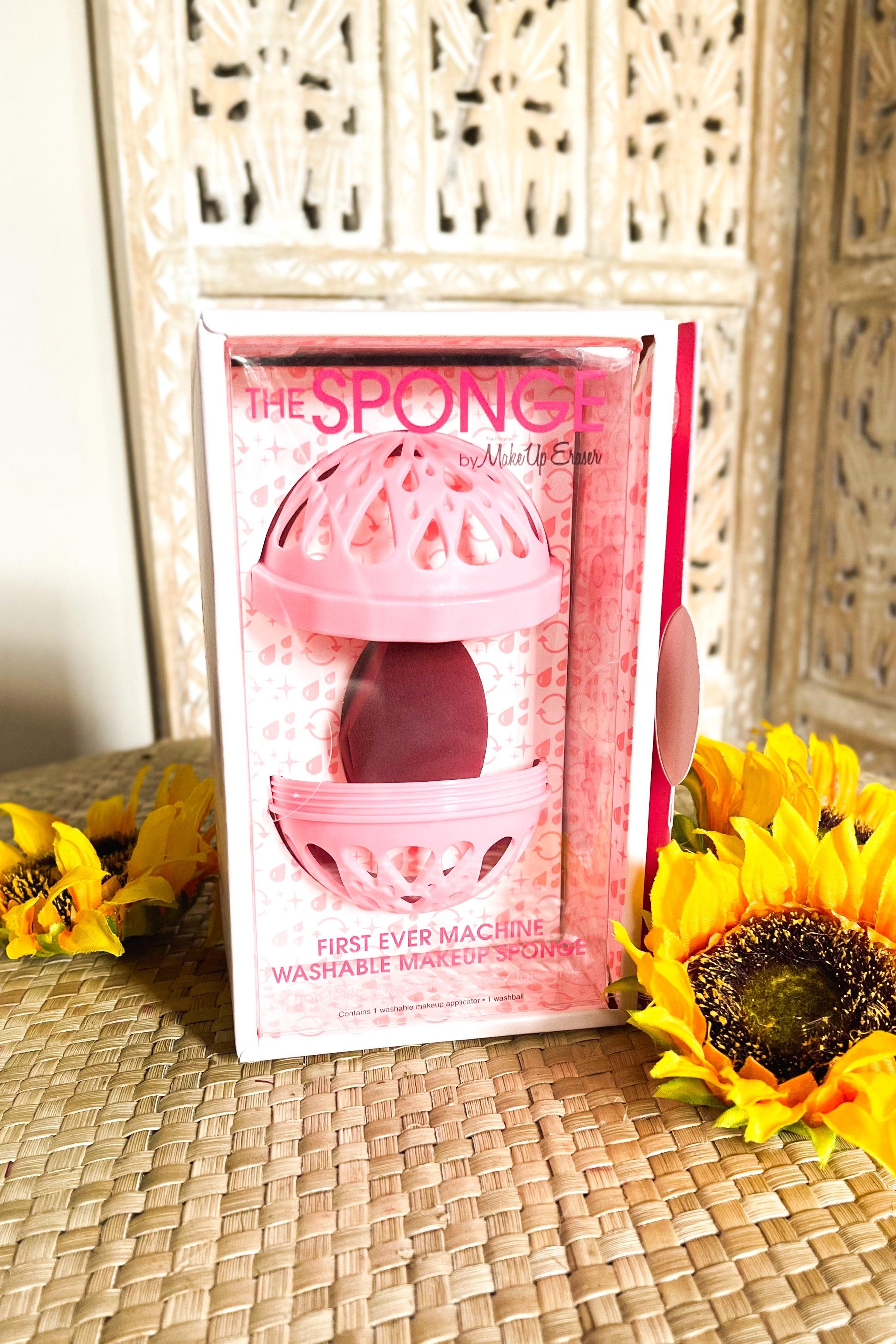 Pink makeup sponge with ventilation case packaging beside bright yellow sunflowers on woven surface