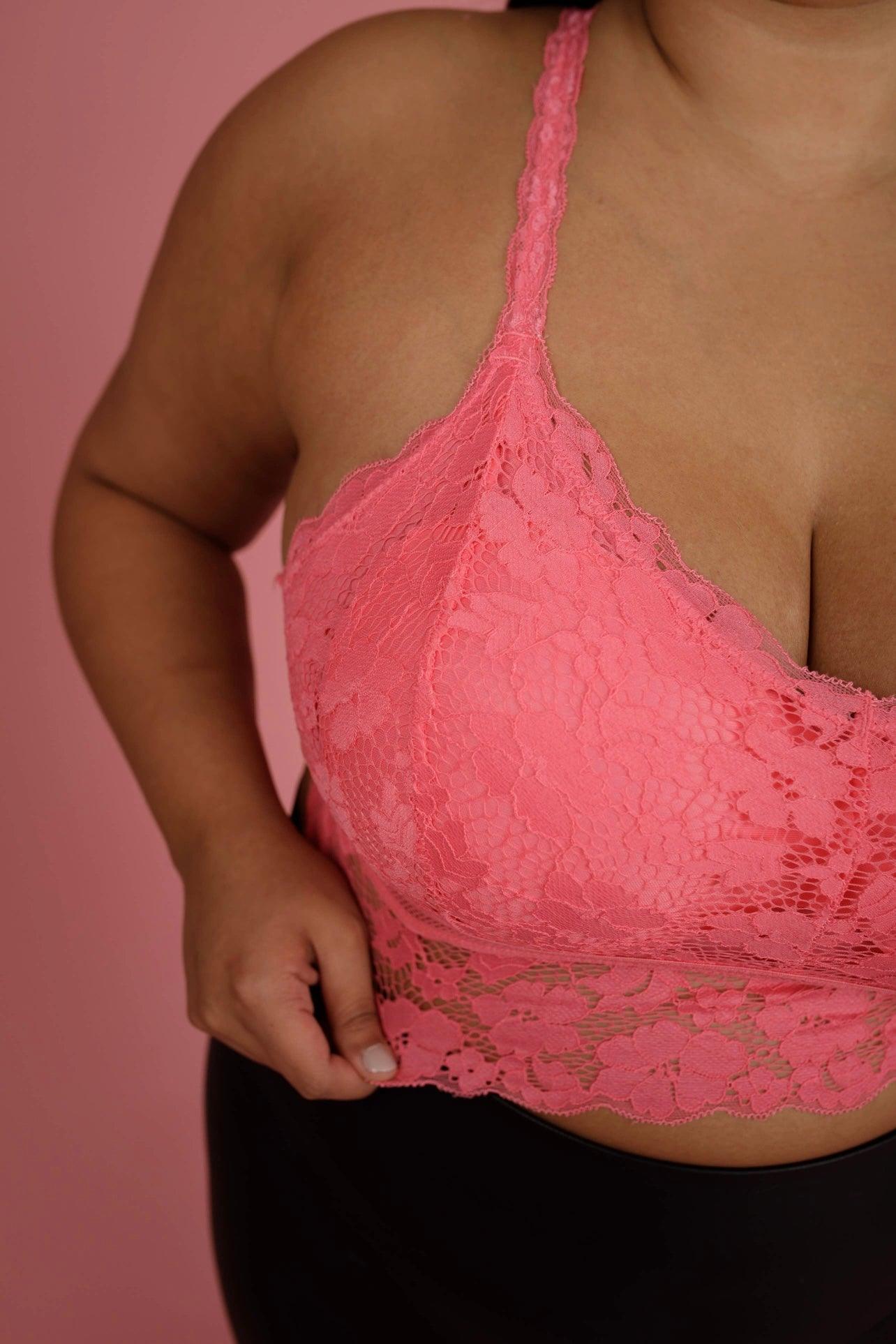 Close-up of a person wearing a pink lace bralette with floral pattern against a matching pink background