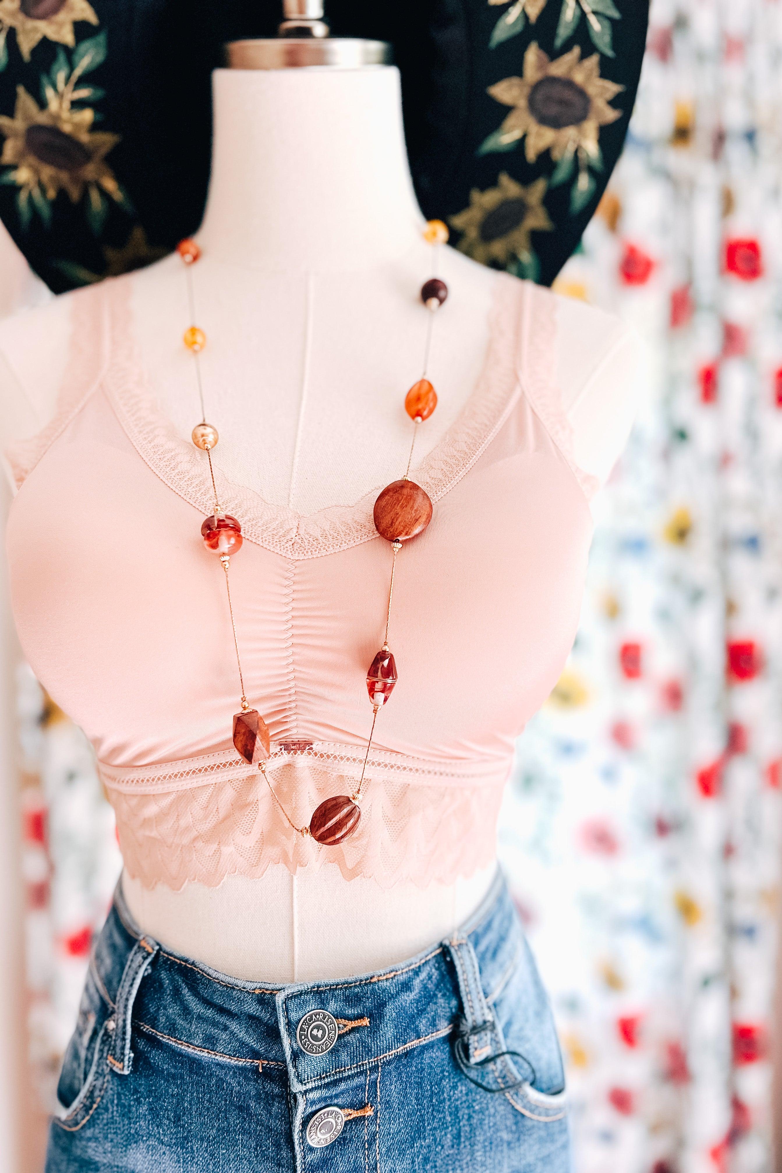 Light pink bralette with lace trim paired with blue denim jeans on a mannequin with colorful background