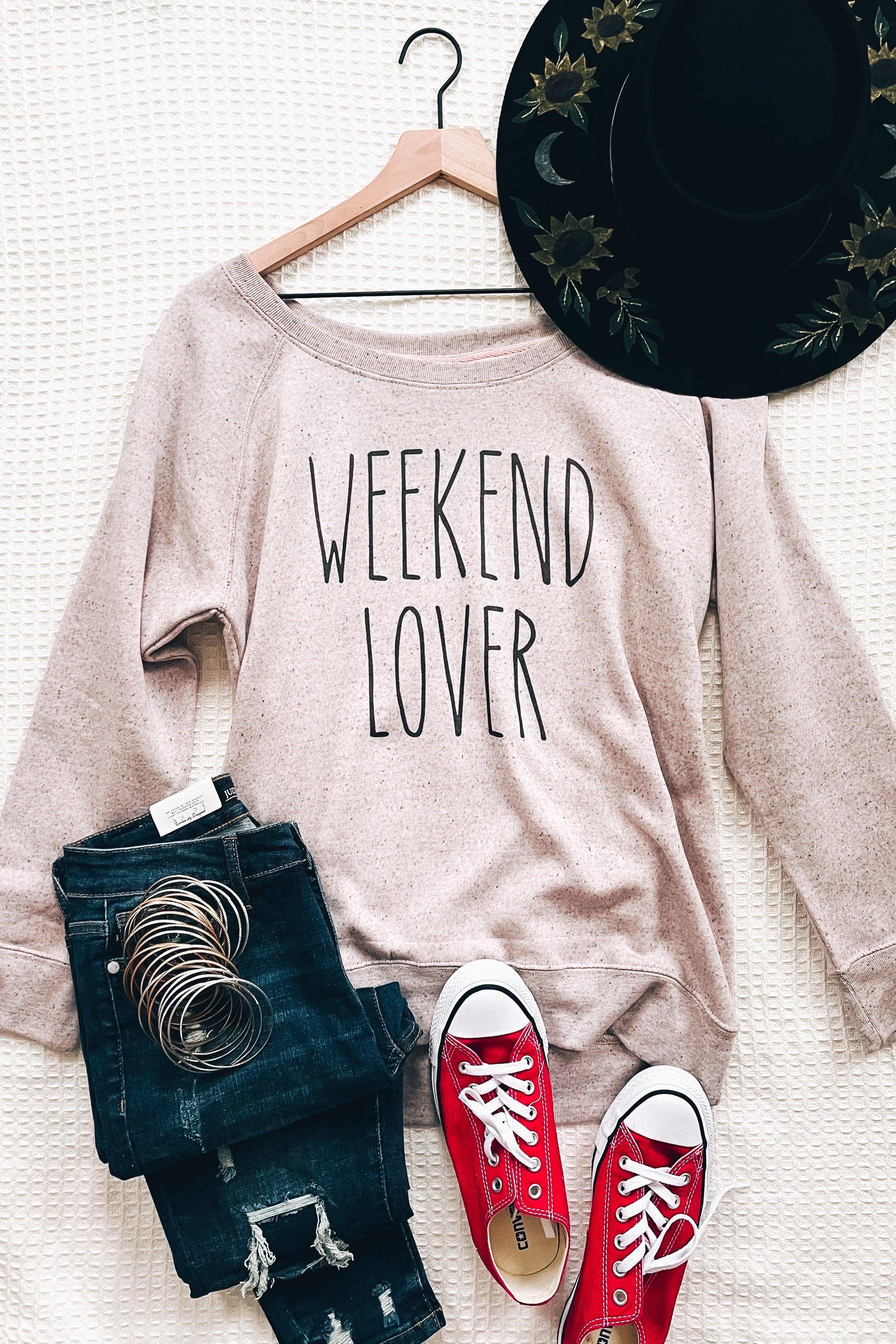 Blush relaxed scoop neck pullover printed with Weekend Lover paired with distressed dark jeans, red sneakers, and black embroidered hat