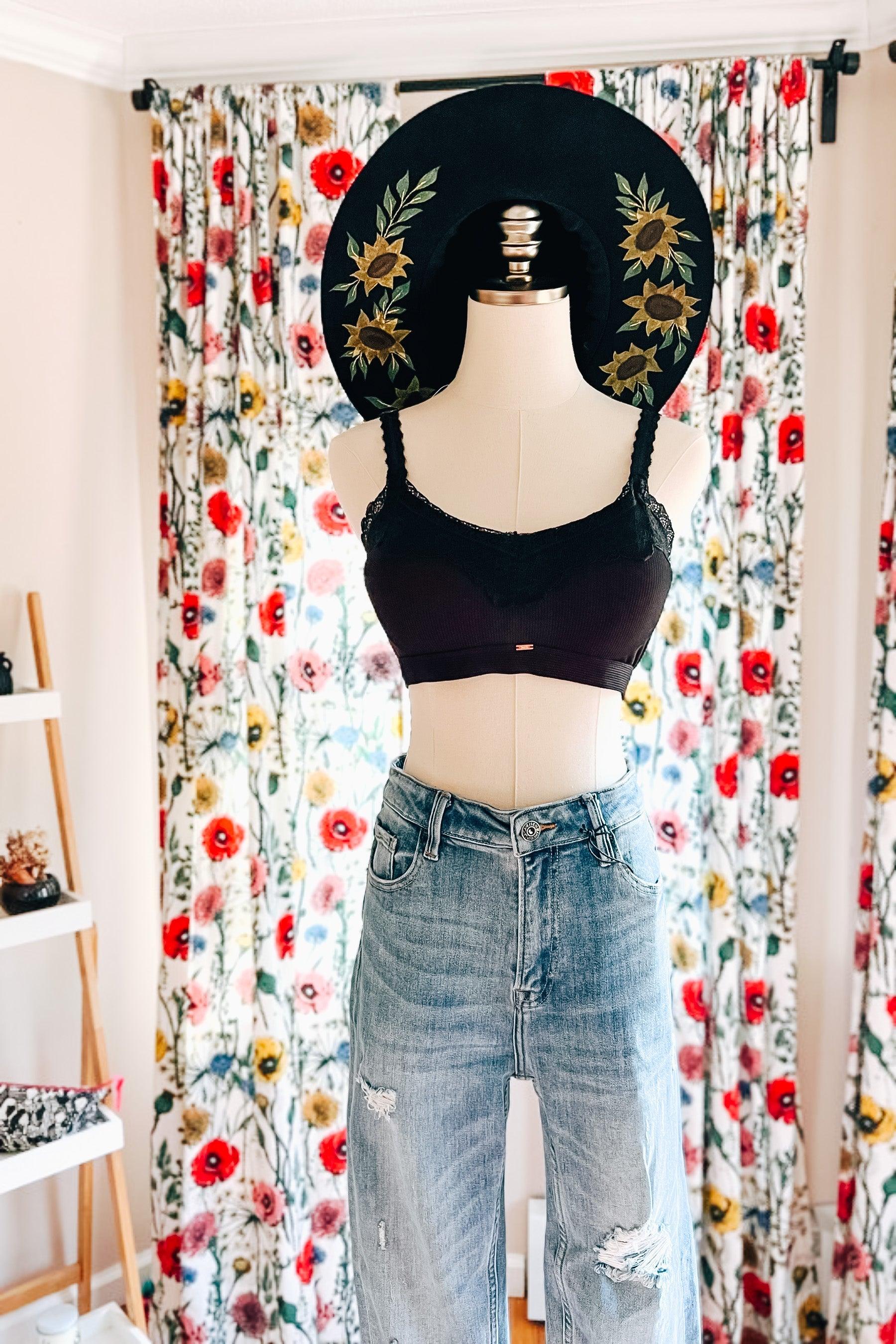 Mannequin dressed in black lace-trim bralette paired with distressed high-waisted jeans in bright floral room setting