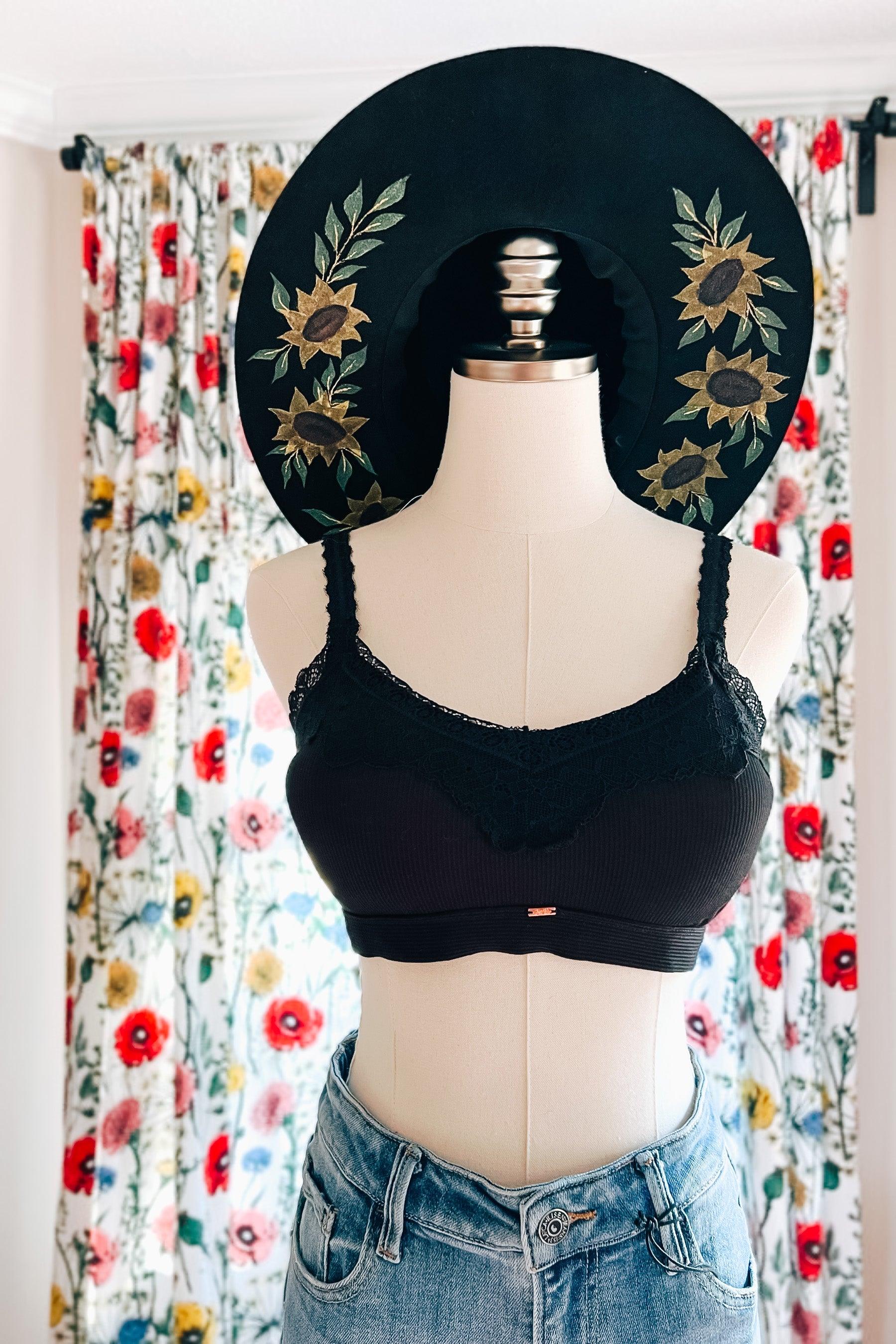 Mannequin dressed in black lace-trim bralette paired with high-waisted denim jeans and wide-brim hat with floral embroidery