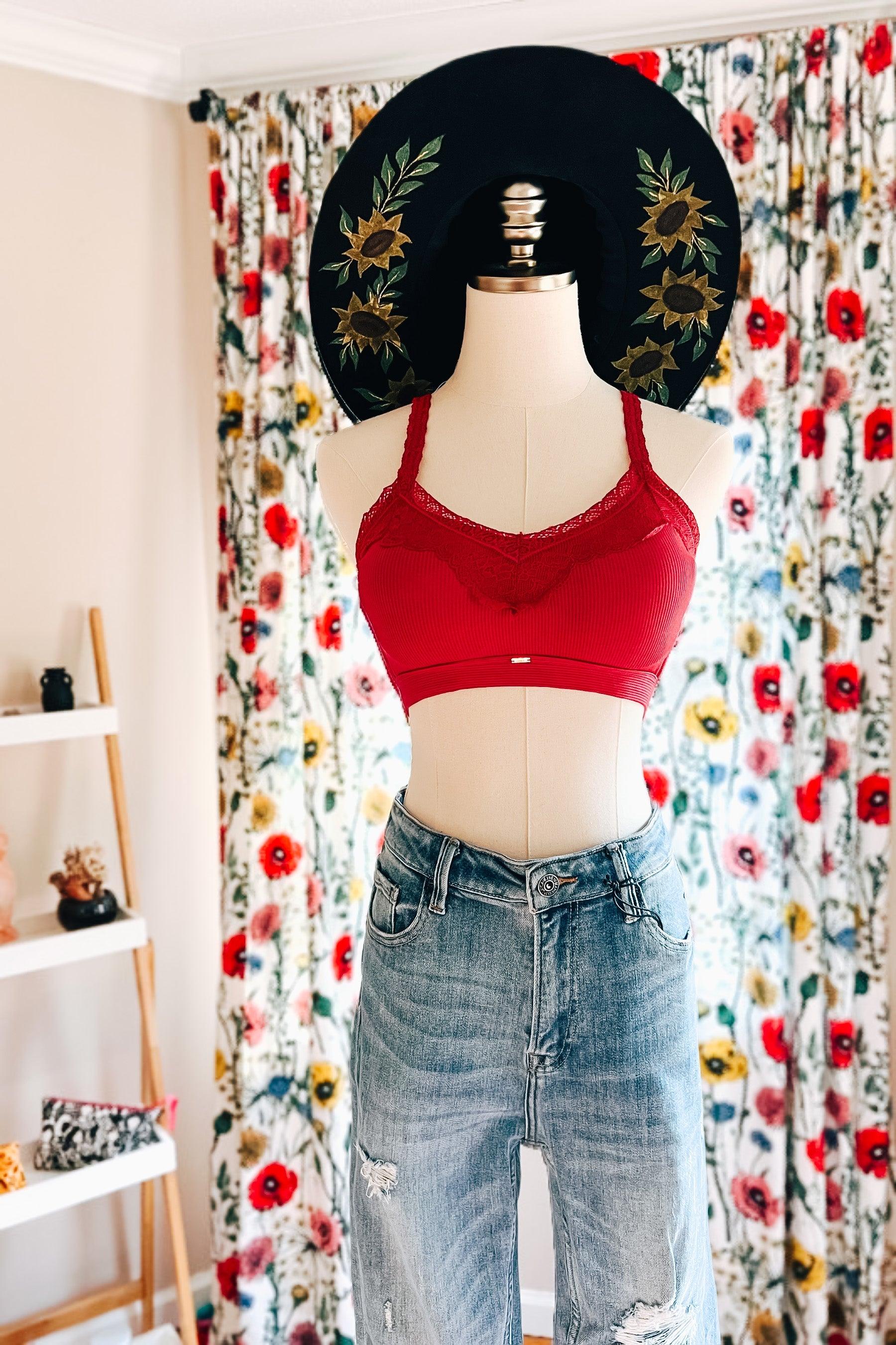 Mannequin dressed in wine-colored lace trim bralette paired with distressed high-waisted denim jeans and black hat with sunflower embroidery